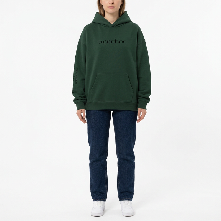 Model wearing the Gather Essential Hoodie in dark green on a white studio background