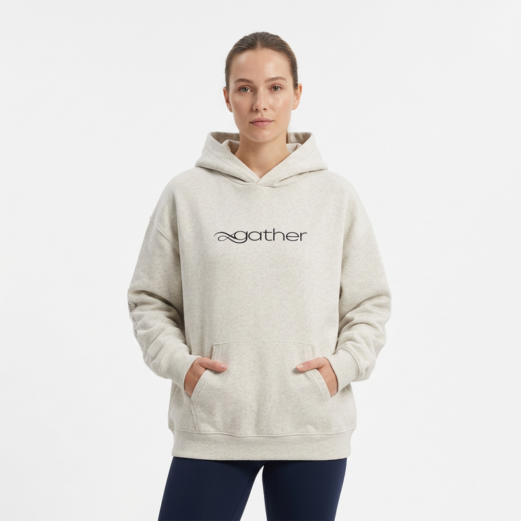 Model wearing the Gather Essential Hoodie in light gray on a white studio background